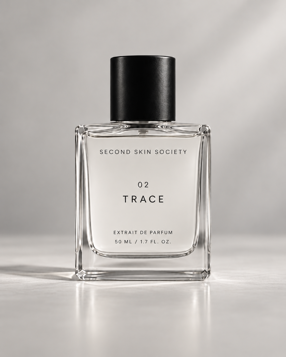 TRACE Extrait de Parfum bottle with black cap on pale stone