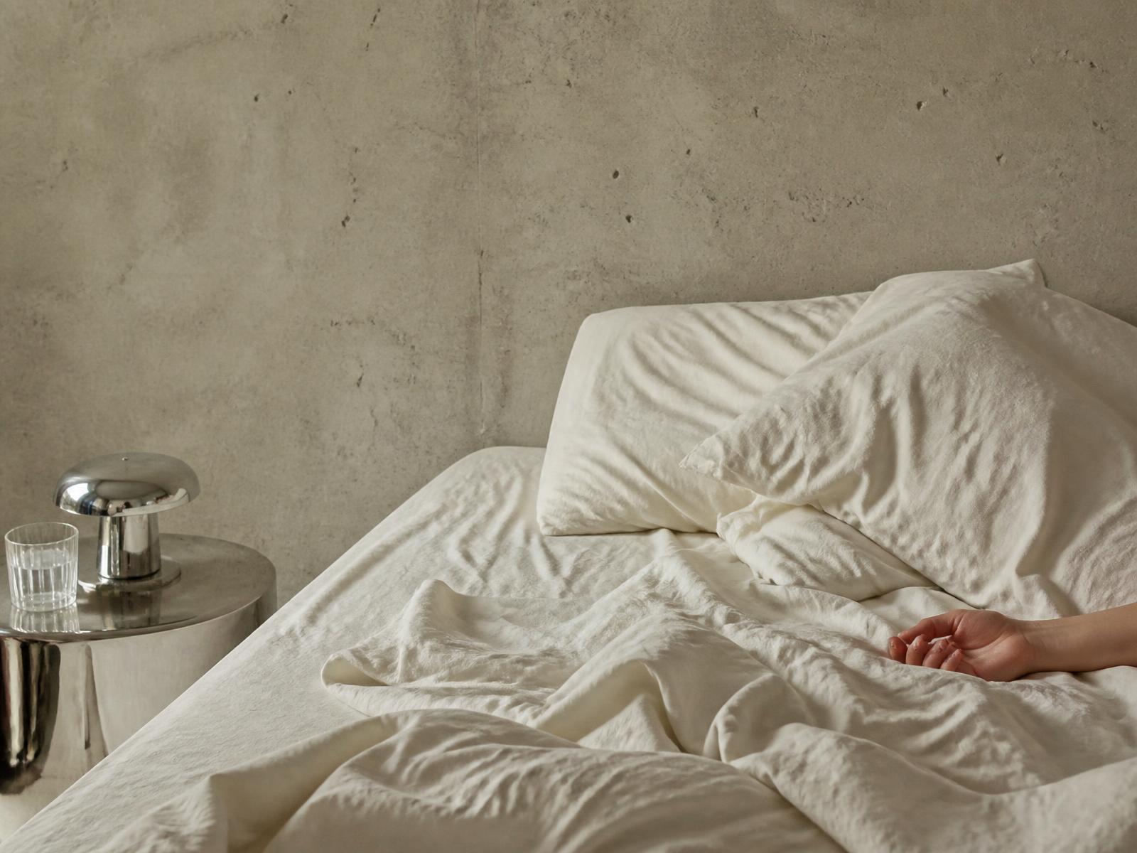 Unmade ivory bed in quiet morning light