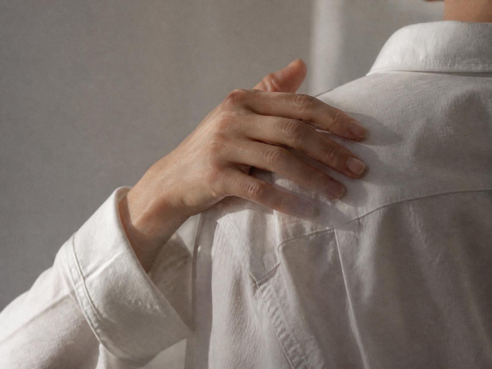 A hand resting on a shoulder covered by a white shirt